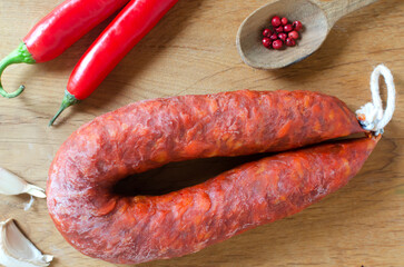 Spanish Chorizo sausage with red pepper, paprika and garlic on a wooden cutting board with a knife...