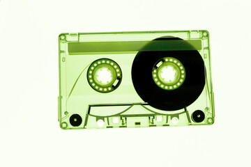 close-up of audio cassette clear recordable mixed tape isolated on white illuminated background nostalgic retro vintage music photography with green tint