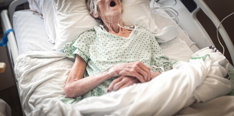 Fototapeta premium Portrait of senior woman sick lying in hospital bed, getting treatment