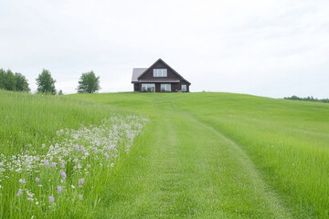 A large house sits on a hill with a grassy field in front of it