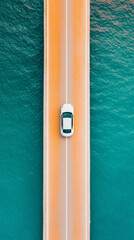 Fototapeta premium Aerial view of white car driving on coastal road over turquoise water, showcasing serene landscape