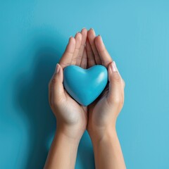 Fototapeta premium Female hands on a blue background holding a blue heart. The concept of donations and family insurance, World Heart Day. valentine's day.