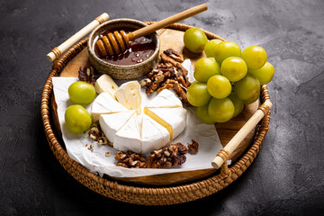 A colorful cheese platter with honey, sweet grapes, and crunchy walnuts, perfect for any gathering...