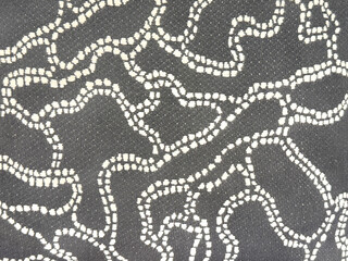 Close up of dark grey fabric with random curves and worm shape pattern. White sewn dotted curves on grey background. Suitable for wall paper and fabric. Seamless background texture