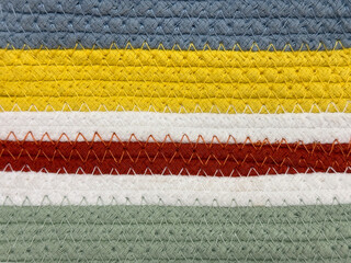 Close up of knitted colorful fabric in blue, yellow, white, red, and green horizontal stripes pattern. Seamless knitted wool fabric background texture, suitable for sweater or bags.