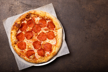 Homemade italian pizza with mozzarella, pepperoni sausages, on a dark background top view copy space for text