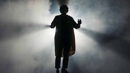 A silhouette of a man floating in mid-air, as if hung by invisible strings. His arms dangle lifelessly, and the mist swirls unnaturally around him