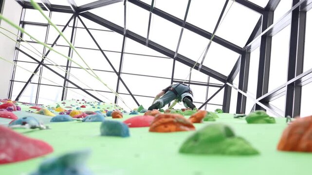 A girl climbs on a climbing wall in door. Exercise, activity, fun.