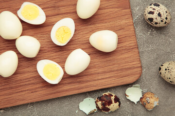 Fototapeta premium Boiled quail eggs on cutting board on grey concrete background. Easter
