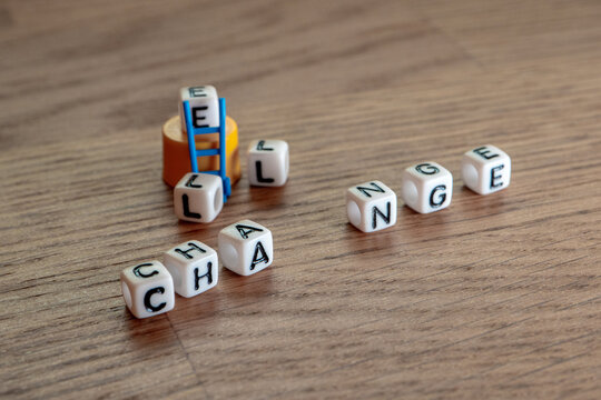 Naklejki Removing white cubes with letters l and e of the word challenge creating new word change on wooden background 