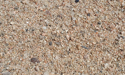 Stones and sand in the summer day. Yellow sand on the beach near a sea.