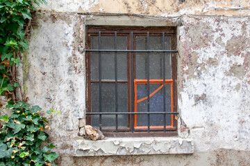 Close dirty rustic aged window in old house on the street.