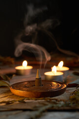 Incense burning in dim light with candles creating a tranquil atmosphere