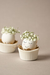Creative Easter concept with eggs in cupcake pan lines. Bright and airy concept of white easter egg with cute face