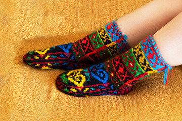 Beautiful wool socks made of multicolored threads on the girl's feet