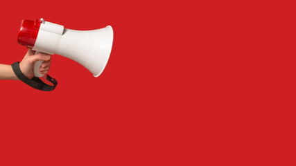 Megaphone in woman hands on a red background.