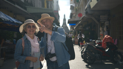 Elderly couples and their activities on the road at the end of the alley where there is a pagoda, Thailand