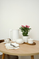 A beautifully serene dining table setting features an elegant flower pot, a lovely tea set, creating a cozy ambiance.