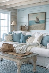 A serene living room features a comfortable sofa adorned with cushions in soft blues and whites. Natural light streams in from large windows, highlighting nautical artwork