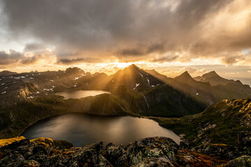 sonnenstrahlen brechen durch wolken vor berglandschaft