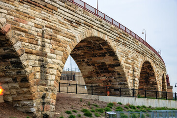A stone arch bridge with a red railing