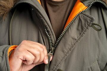 Man zipping up warm winter jacket with fur hood © Maria Vitkovska