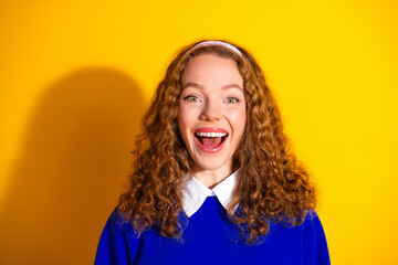 Euphoric Young Woman Smiling Brightly in Stylish Blue Attire Against a Vibrant Yellow Background