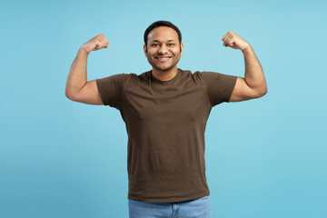 Strong man flexing muscles showing biceps on blue background