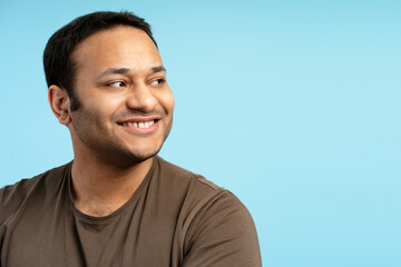 Smiling middle aged Indian man smiling and looking away on blue background