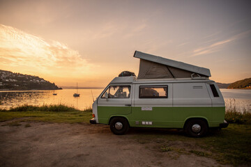 Kleiner Campingbus mit Klappdach am Meer zum Sonnenuntergang