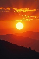 A brilliant orange sun sinks slowly below a wispy cloud layer, serene landscape, bright light