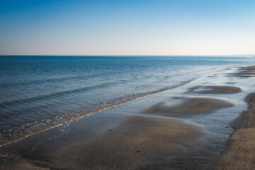 Tranquil beach with gentle waves and wet sand..