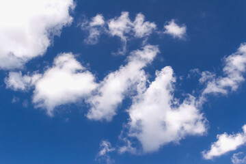Fluffy white cumulus clouds floating gently over vibrant blue sky, representing peaceful atmospheric conditions with natural tranquility and meteorological beauty