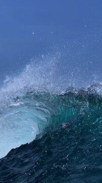 Perfect blue ocean wave breaks on the shore in Indonesia.Slow motion video.View from the water.Vertical video
