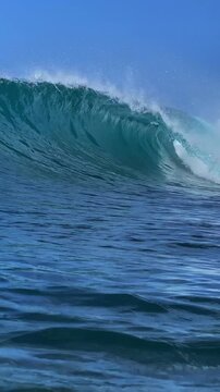 Perfect blue ocean wave breaks on the shore in Indonesia.Slow motion video.View from the water.Vertical video