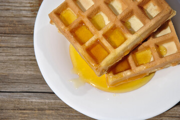 fresh delicious Belgian waffles with honey on a white plate top view