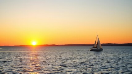 Scenic sunset over Lake Superior with sail boat sailing peacefully on the calm waters, sail boat, nautical