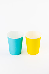 top shot on white background two paper cups for coffee and tea painted in yellow and blue disposable tableware attributes for trips, recreation and picnics eco cups waterproof