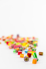 on white background in a small multi-colored sugar caramels with different flavors and patterns lie children's favorite sweets a large selection risk of caries blood sugar excess weight