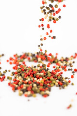 on white background a pile of mixed large aromatic peppers black red and white the main seasoning for food peppercorns indian and european spices the best variety spill from the top