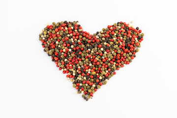 white background a pile of mixed large aromatic peppers black red and white the main seasoning for food peppercorns indian and european spices pepper laid out in the shape of a heart