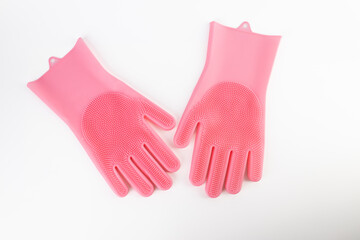 On white background lie large thick rubber pink gloves with texture for easy dish washing replacement sponge for dishes care of hands protection from chemicals