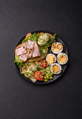 Healthy breakfast consisting of boiled eggs, slices of ham, tomatoes, green beans, aioli sauce