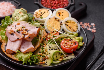 Healthy breakfast consisting of boiled eggs, slices of ham, tomatoes, green beans, aioli sauce