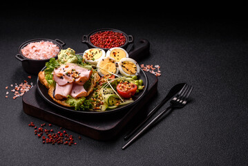 Healthy breakfast consisting of boiled eggs, slices of ham, tomatoes, green beans, aioli sauce