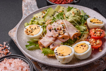 Healthy breakfast consisting of boiled eggs, slices of ham, tomatoes, green beans, aioli sauce