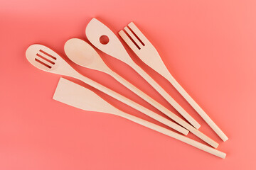 close-up on soft pink background lie new kitchen light wooden utensils of different shapes spatulas for tephlon coating natural wood handmade different types of use