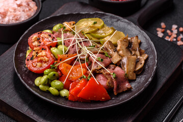 Warm salad consisting of slices of roast beef, greens, tomatoes, cucumbers, green beans