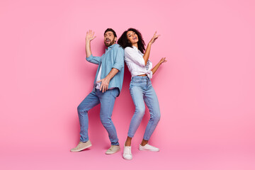 Fototapeta premium Couple Posing Playfully Against Pink Background in Casual Denim Outfits