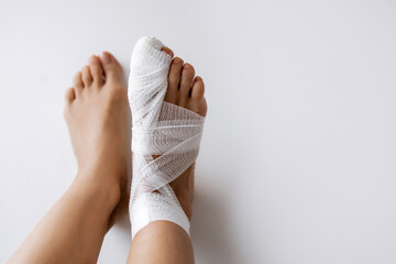 Fracture of the big toe. Bandaged foot with white bandage on a light background. Medical concept. Copy Space